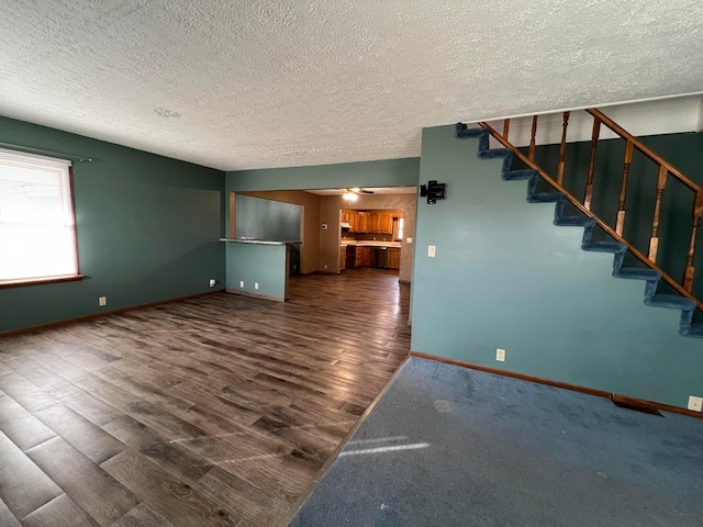 unfurnished living room featuring dark hardwood / wood-style flooring, a textured ceiling, and ceiling fan