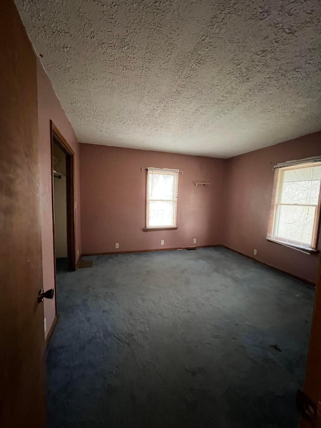 carpeted spare room with a textured ceiling