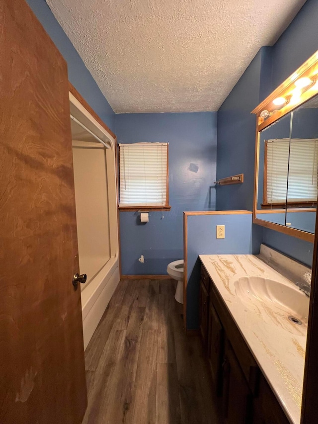 bathroom featuring wood-type flooring, toilet, vanity, and a textured ceiling