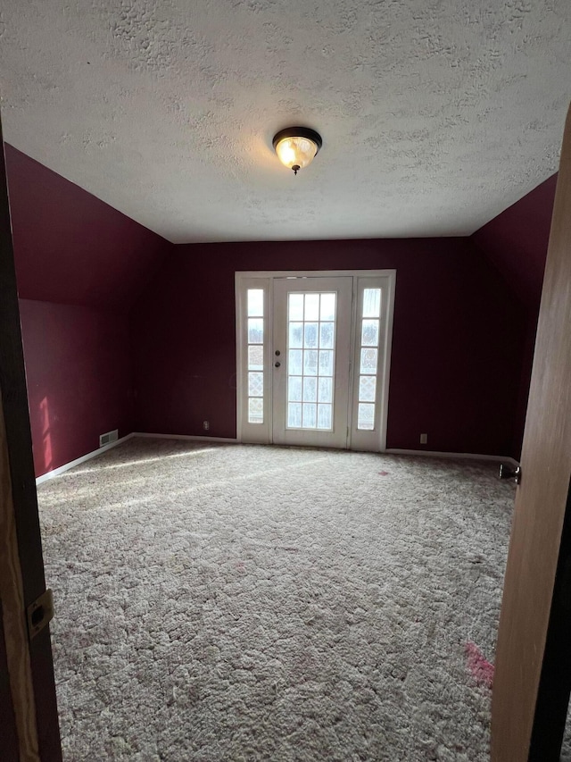 empty room featuring lofted ceiling, carpet flooring, and a textured ceiling