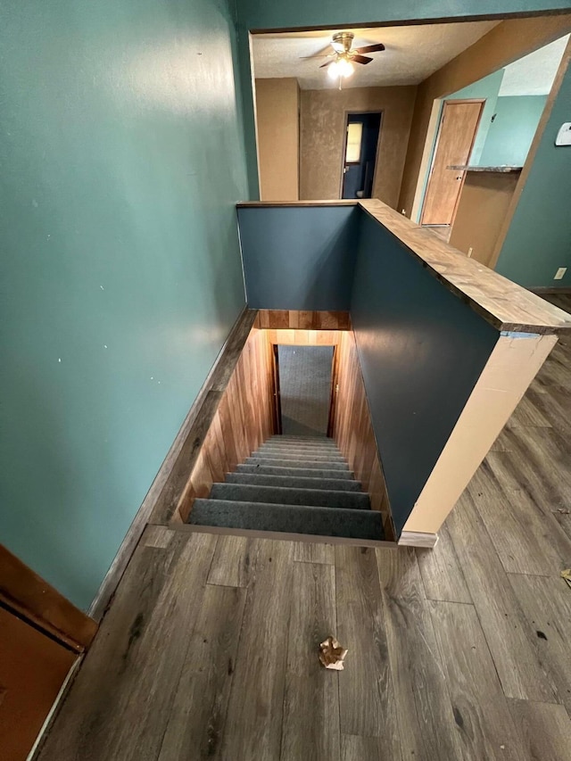 stairway with hardwood / wood-style flooring and ceiling fan