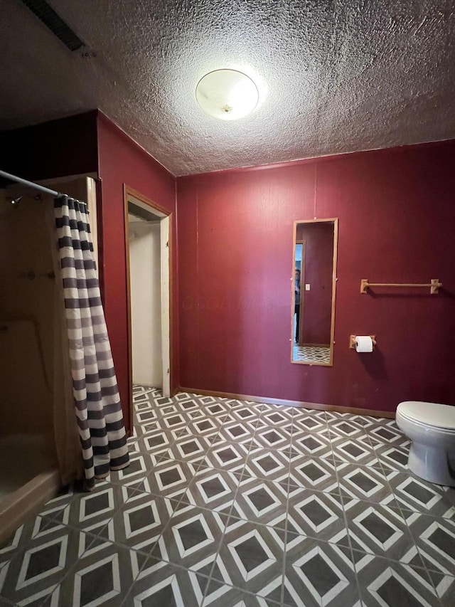 bathroom featuring toilet, a textured ceiling, and a shower with shower curtain