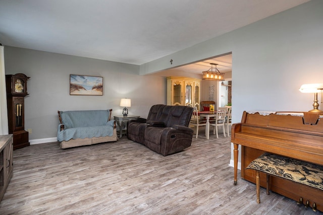 living area with a notable chandelier, baseboards, and wood finished floors