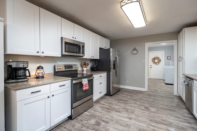 kitchen featuring stainless steel appliances, washer / clothes dryer, light wood-style flooring, white cabinetry, and light stone countertops