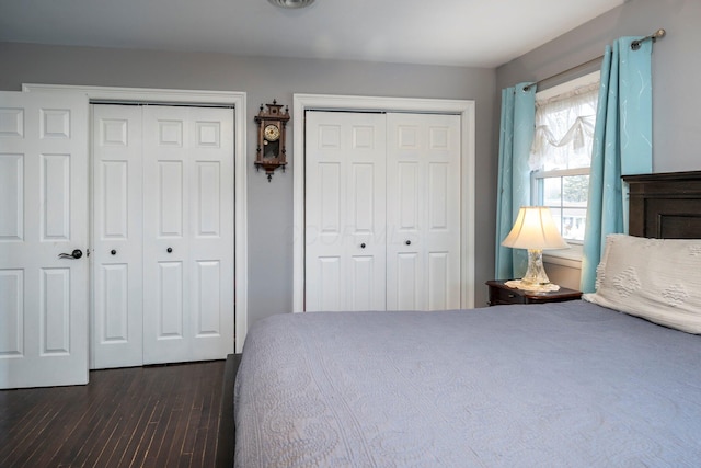 bedroom with dark wood finished floors and two closets