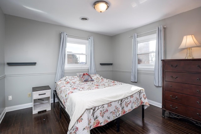 bedroom with baseboards, multiple windows, visible vents, and dark wood-type flooring