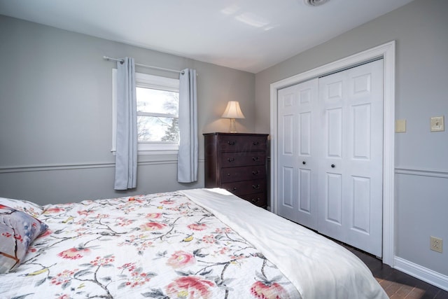 bedroom featuring dark wood-style floors, a closet, and baseboards