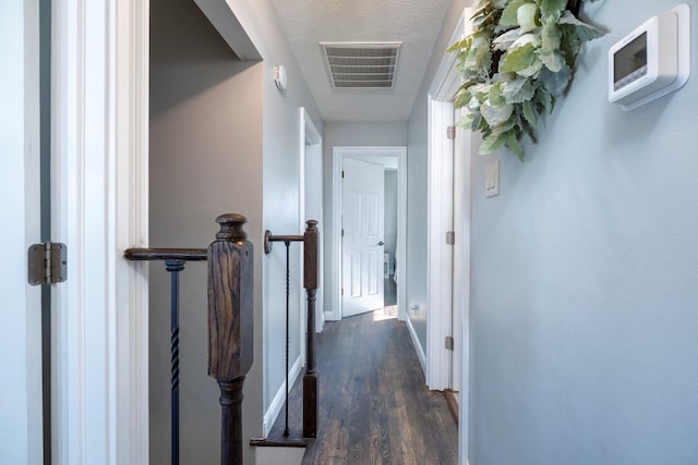 corridor with dark wood finished floors, visible vents, and baseboards