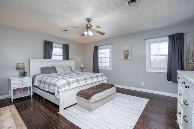 bedroom with visible vents, multiple windows, baseboards, and dark wood finished floors