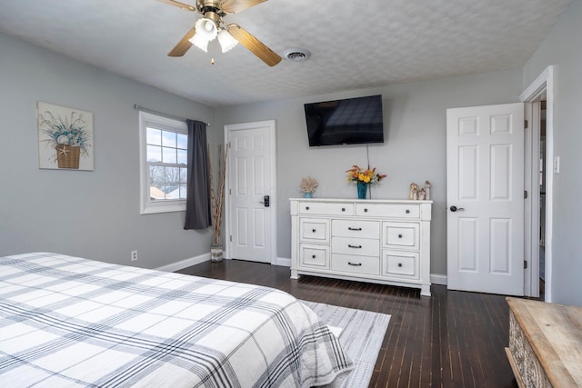 bedroom featuring a textured ceiling, dark wood finished floors, visible vents, and baseboards