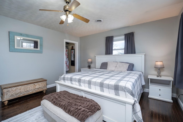 bedroom with dark wood-style flooring, a ceiling fan, visible vents, baseboards, and a spacious closet