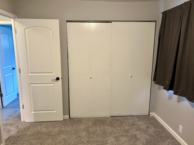 unfurnished bedroom featuring light colored carpet and a closet