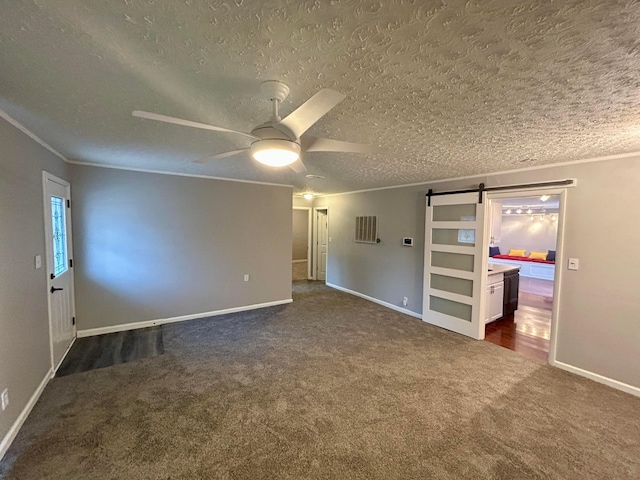 spare room with ornamental molding, a barn door, ceiling fan, and dark carpet