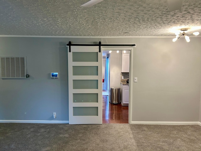 carpeted spare room featuring crown molding, a barn door, and a textured ceiling