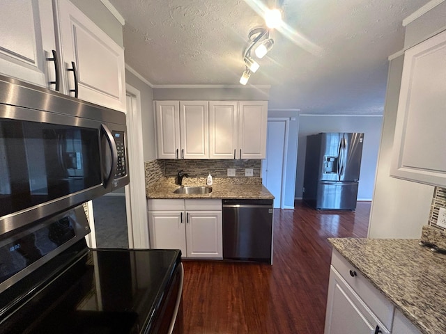 kitchen featuring dark wood-type flooring, sink, light stone counters, appliances with stainless steel finishes, and white cabinets