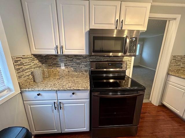 kitchen with white cabinetry, backsplash, stainless steel appliances, and light stone countertops