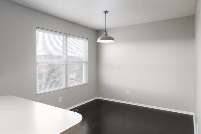 unfurnished dining area with dark hardwood / wood-style floors and a textured ceiling