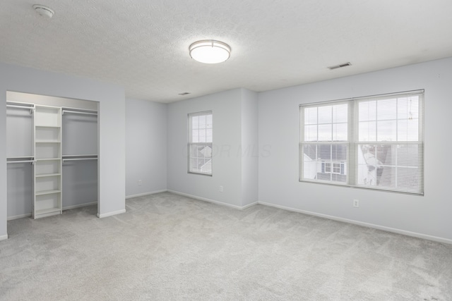 unfurnished bedroom featuring light carpet, a textured ceiling, and a closet