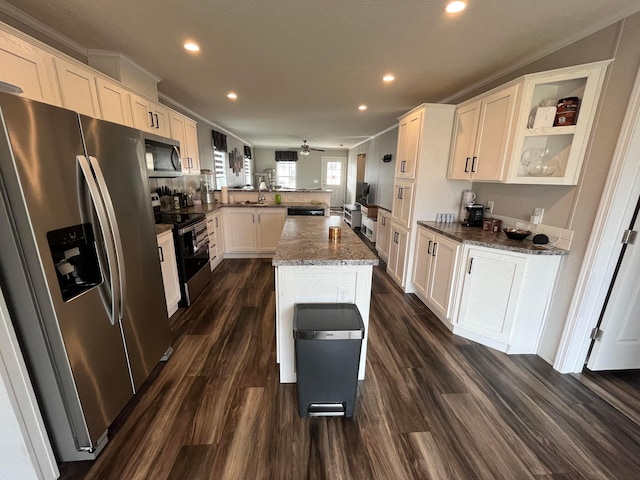 kitchen featuring white cabinetry, dark stone counters, kitchen peninsula, a kitchen island, and stainless steel appliances