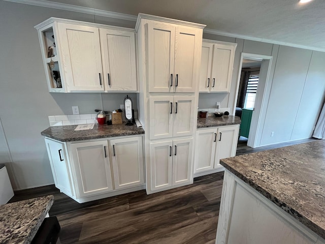 kitchen featuring white cabinetry, dark hardwood / wood-style flooring, crown molding, and dark stone counters