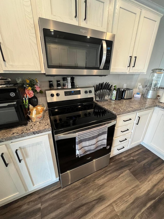 kitchen featuring white cabinetry, stainless steel appliances, light stone countertops, and dark wood-type flooring