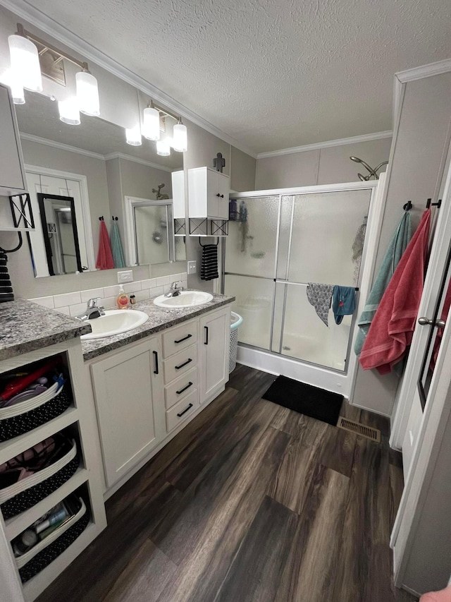 bathroom featuring wood-type flooring, ornamental molding, vanity, and a shower with shower door