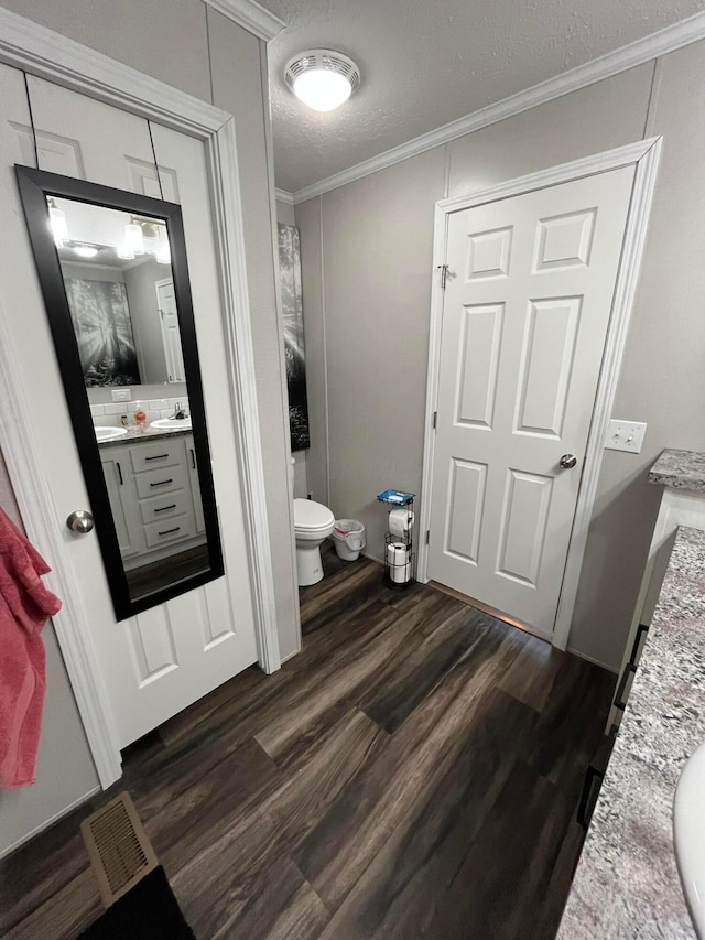 bathroom featuring hardwood / wood-style floors, vanity, ornamental molding, a textured ceiling, and toilet