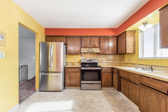 kitchen with appliances with stainless steel finishes, sink, a textured ceiling, and backsplash