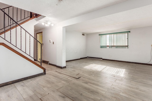 spare room with a notable chandelier, light hardwood / wood-style flooring, and a textured ceiling