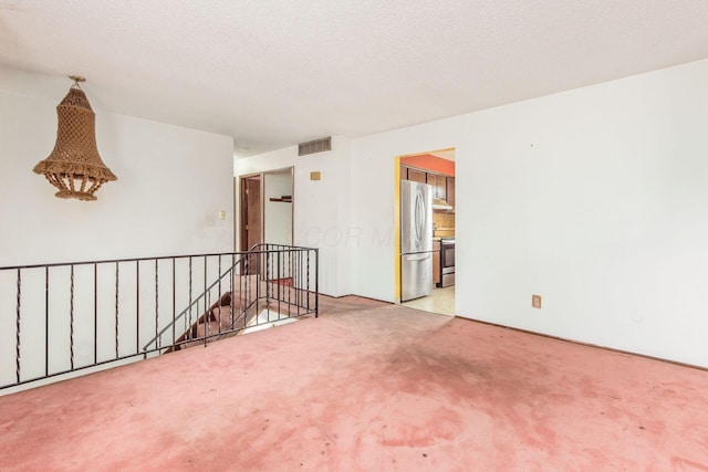 carpeted empty room with a textured ceiling