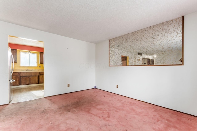 carpeted spare room featuring sink and a textured ceiling