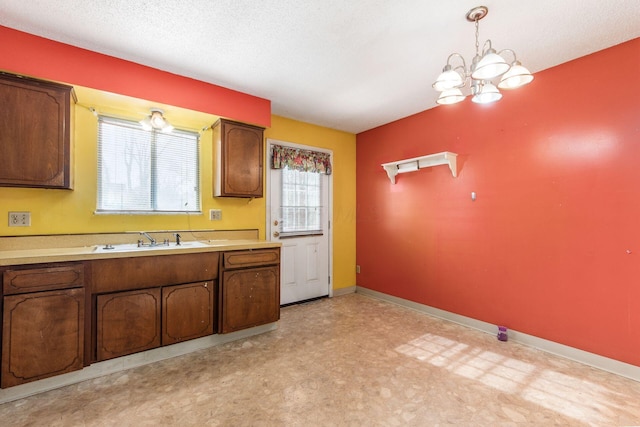 kitchen with hanging light fixtures, sink, a notable chandelier, and a textured ceiling