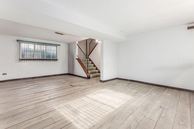 spare room featuring light hardwood / wood-style floors and a textured ceiling