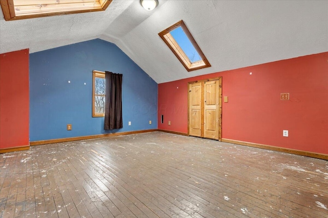 bonus room with hardwood / wood-style flooring, vaulted ceiling with skylight, and a textured ceiling