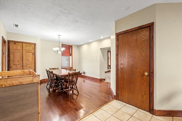 dining area featuring light hardwood / wood-style flooring, a chandelier, and a textured ceiling