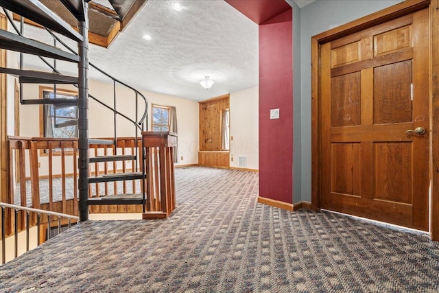 corridor with a textured ceiling and dark carpet