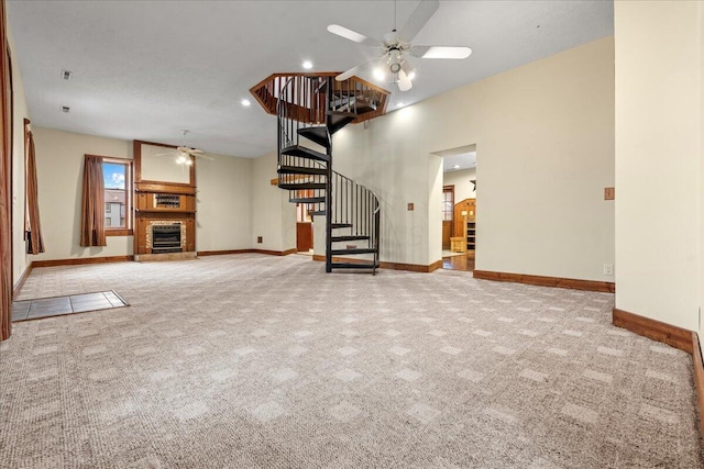 unfurnished living room featuring a high ceiling, light colored carpet, and ceiling fan