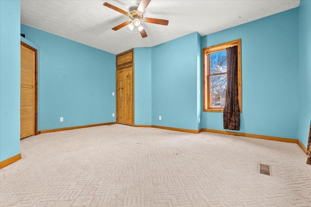 unfurnished bedroom featuring ceiling fan, light colored carpet, and a textured ceiling