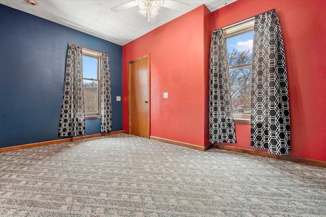 carpeted spare room featuring ceiling fan and plenty of natural light