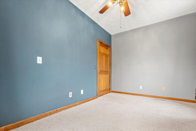 empty room with ceiling fan, lofted ceiling, carpet floors, and a textured ceiling