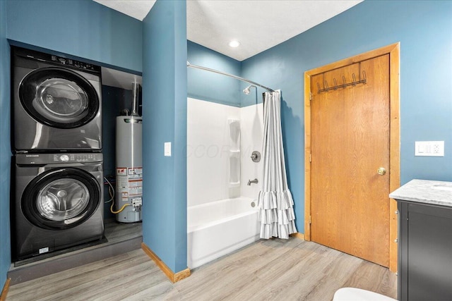 bathroom featuring shower / tub combo with curtain, water heater, hardwood / wood-style floors, stacked washer / dryer, and vanity