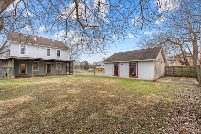 rear view of property featuring a yard, an outdoor structure, and a patio