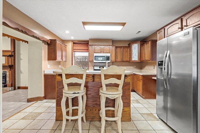 kitchen with stainless steel appliances, light tile patterned floors, and a kitchen bar