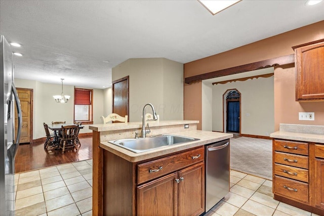 kitchen with sink, a kitchen island with sink, hanging light fixtures, stainless steel appliances, and light tile patterned flooring