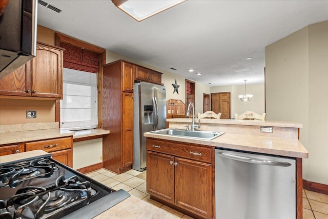 kitchen with appliances with stainless steel finishes, sink, light tile patterned floors, and decorative light fixtures