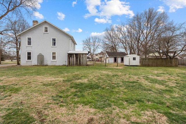 rear view of house featuring a lawn and a storage unit