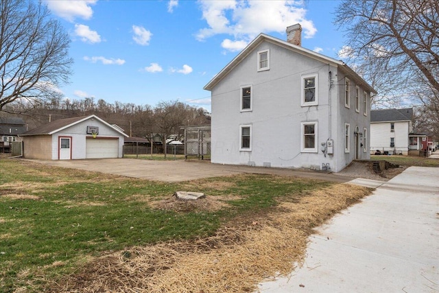 view of home's exterior with a garage, an outdoor structure, and a lawn