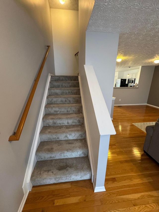 staircase with hardwood / wood-style flooring and a textured ceiling