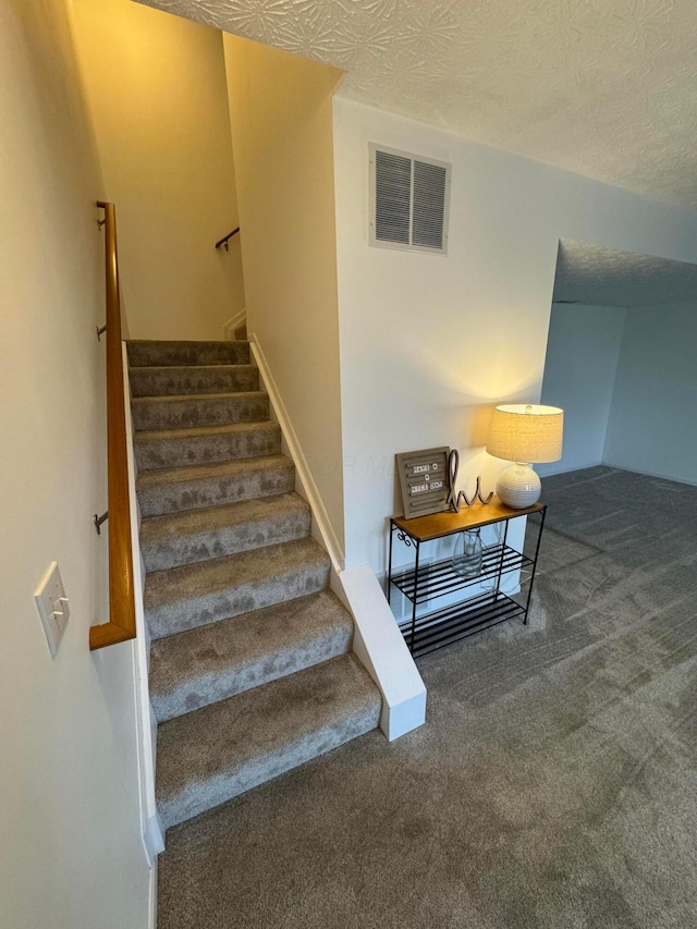 stairs with carpet and a textured ceiling