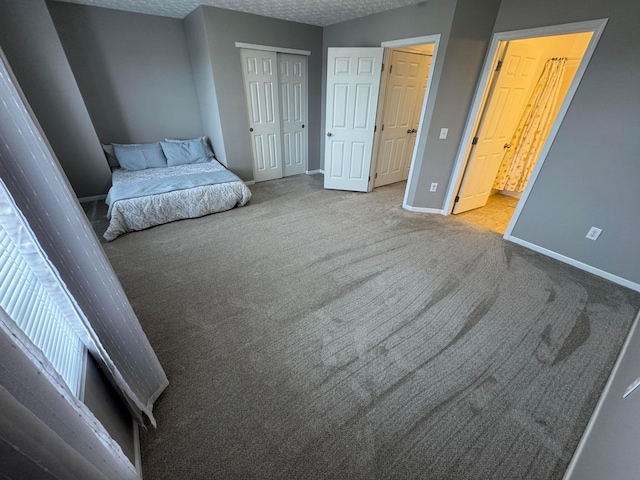 carpeted bedroom with connected bathroom, a closet, and a textured ceiling